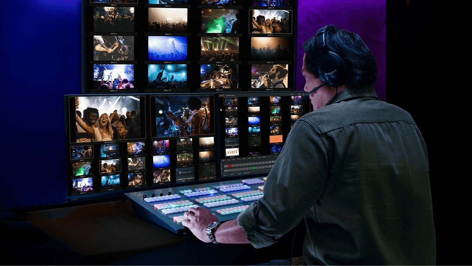 A professional video producer operating a TriCaster control panel in a dark studio, viewing multiple live concert feeds on monitors.